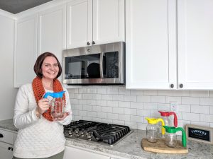Woman holding mason jar spout and handle in kitchen