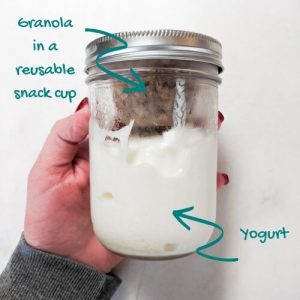 Yogurt in a mason jar with a reusable snack cup containing granola