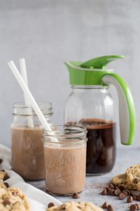 Mason jar with chocolate syrup and an Ergo Spout with two glasses of chocolate milk on the side - 3/4 view