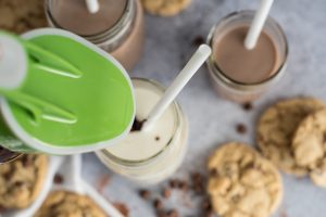 Ergo Spout pouring chocolate syrup from a mason jar into a glass of milk - Looking from the top down