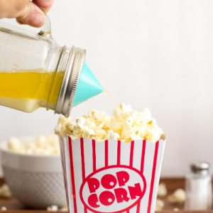 Melted butter in a mason jar with an Ergo Spout Mini dispensing the butter onto popcorn