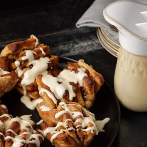 Apple cinnamon roles with caramel icing drizzles over them and a mason jar with an ergo spout