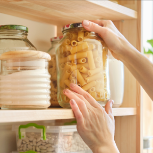 Woman reaching for pasta in a glass jar on a shelf