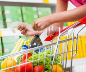 Woman holding a grocery receipt by a shopping cart